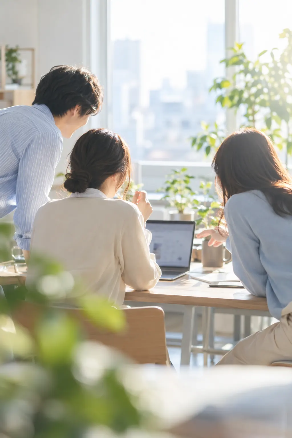 事務所で先輩が後輩にパソコンの画面を見ながら説明している様子
